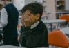 Dziecko zasłaniające twarz dłońmi w szkolnej sytuacji bullyingu